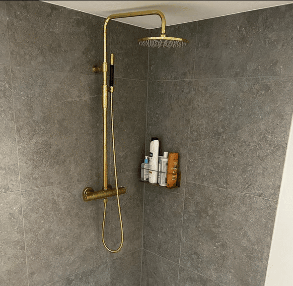 Brusekabine med natursten fliser og brusearmatur i guld