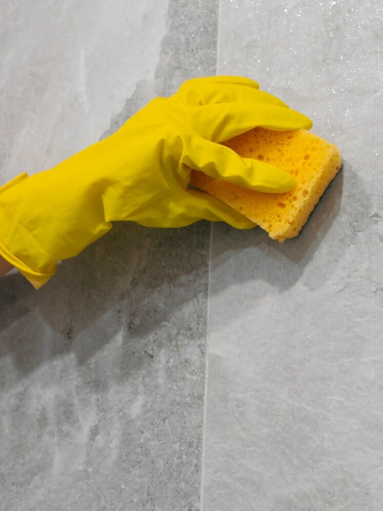 Person if&oslash;rt gul handske holder en skuresvamp