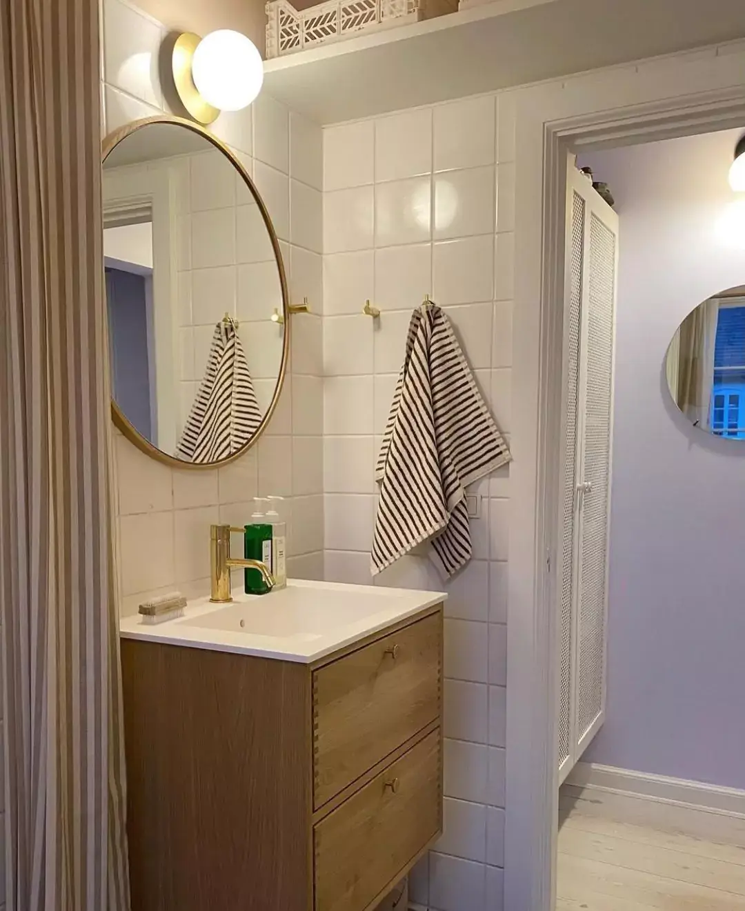 lille badeværelse med rundt spejl og badeværelseslampe